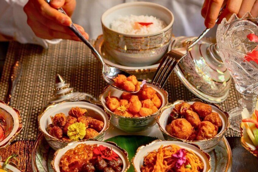 A table with various dishes, including a bowl of rice, several small bowls of fried snacks, and a glass of water. 4
