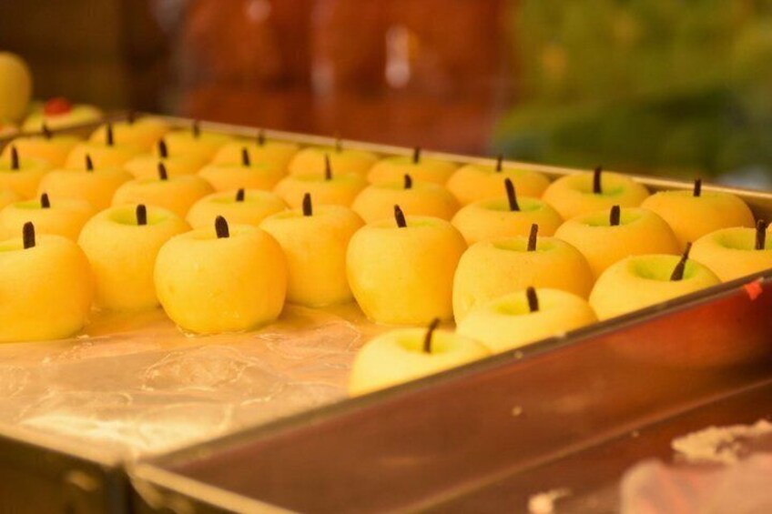 A tray of yellow apples with candles in them. 3