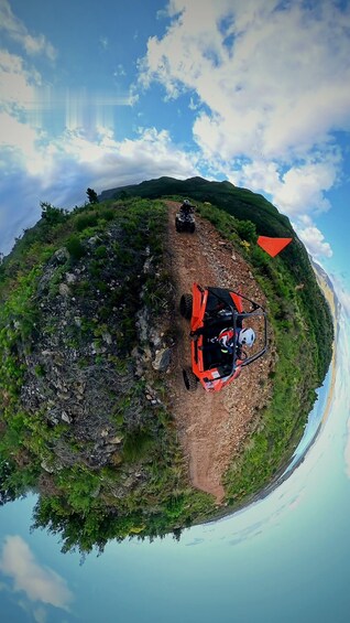 A quad bike on a dirt path surrounded by greenery and a body of water. 3