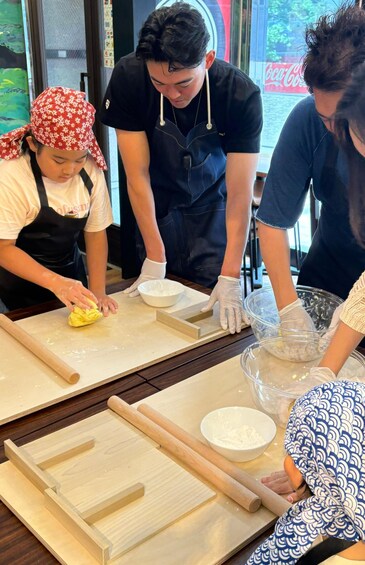 People preparing food with bowls and rolling pins on a wooden table. 3