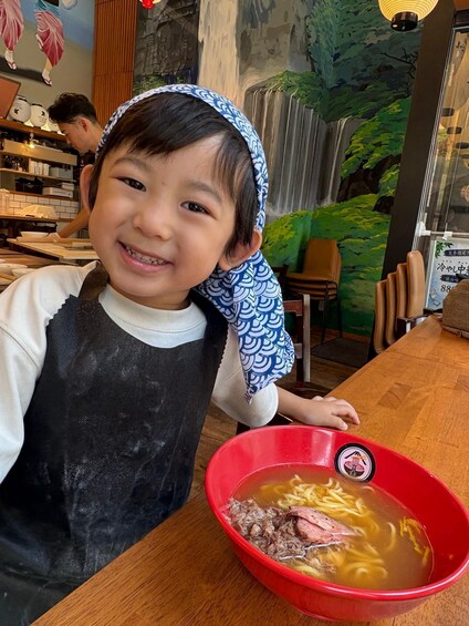 A child at a restaurant with a bowl of ramen. 5