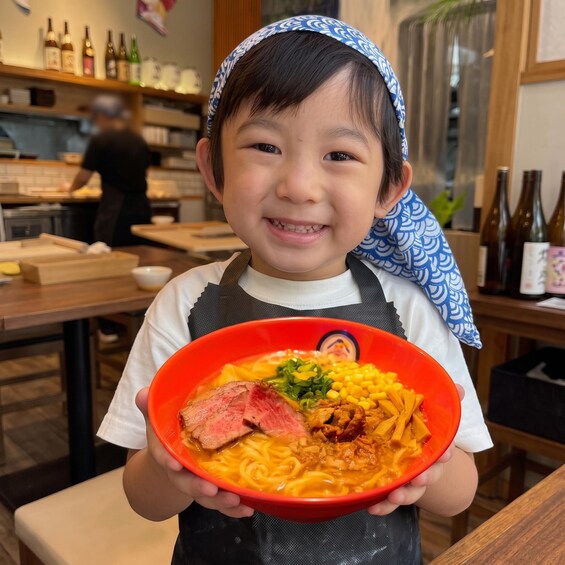 A person holding a bowl of ramen with various toppings. 1