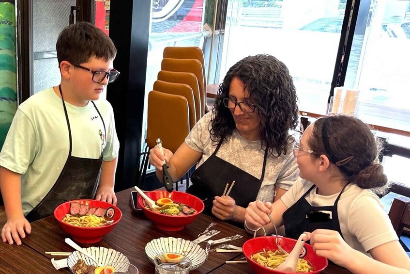 Three people dining at a restaurant with red bowls of food and chopsticks. 5