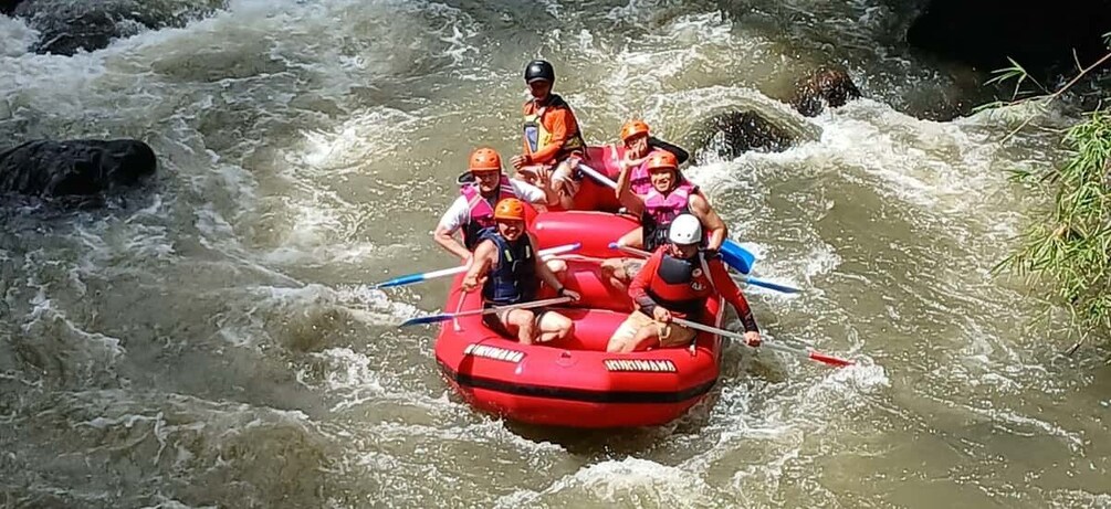 A group of people in a red inflatable raft navigating a river with rapids. 1