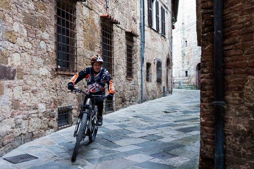 A cyclist riding a bike down a cobblestone street in a historic area with stone buildings. 3