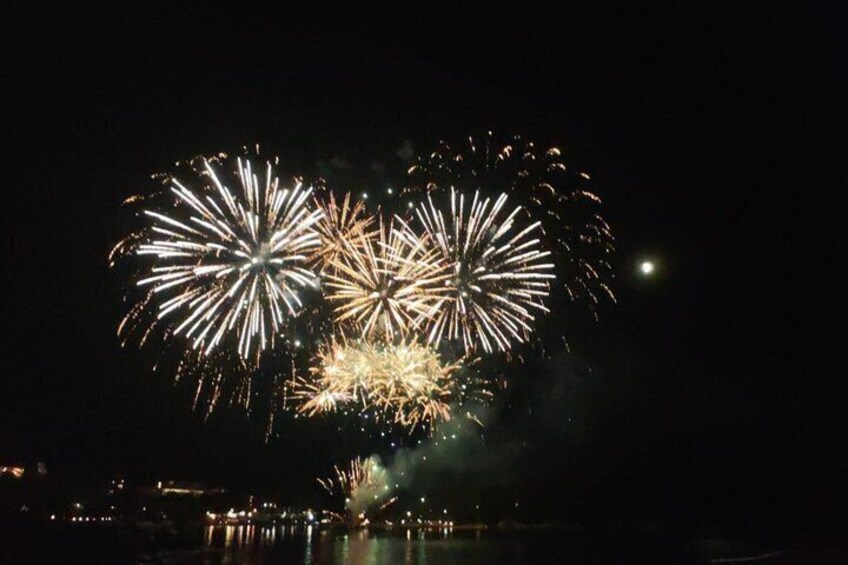 A night sky with multiple fireworks exploding over a body of water. 5