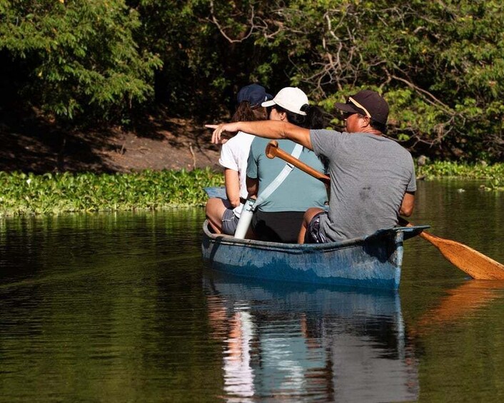 A group of people in a rowboat on a calm river surrounded by greenery. 4