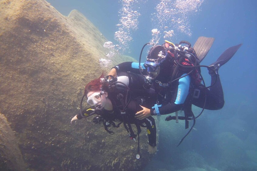 A diver with a scuba tank and fins underwater. 1