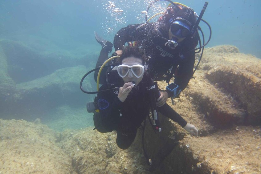 A diver with a scuba mask and breathing apparatus underwater, surrounded by marine life and coral formations. 3