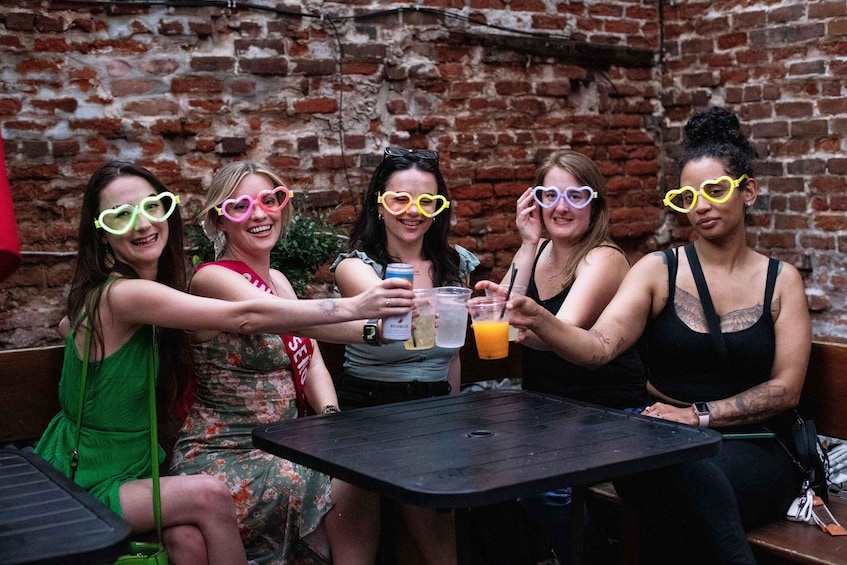 A group of people sitting at a table outdoors with a brick wall in the background. 1