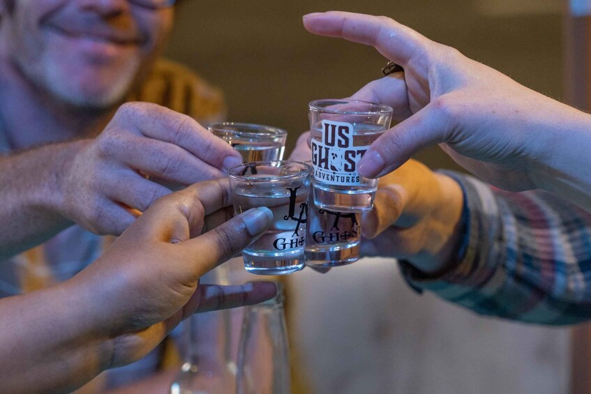 A person holding shot glasses with text on them. 5