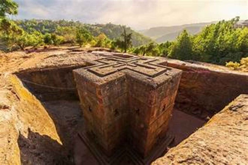 A large stone structure with a geometric pattern, surrounded by a natural landscape with trees and hills. 3