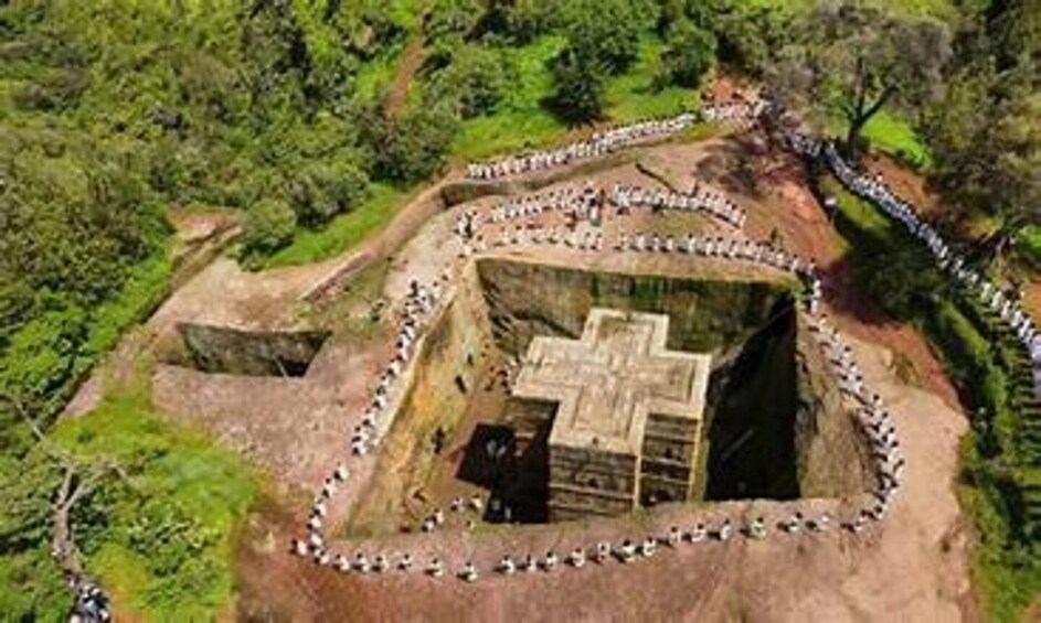 An ancient stone structure surrounded by a stone wall, with a cross-shaped pattern on the floor. 5