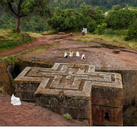 A large stone labyrinth with a central door, surrounded by a forested area. 1
