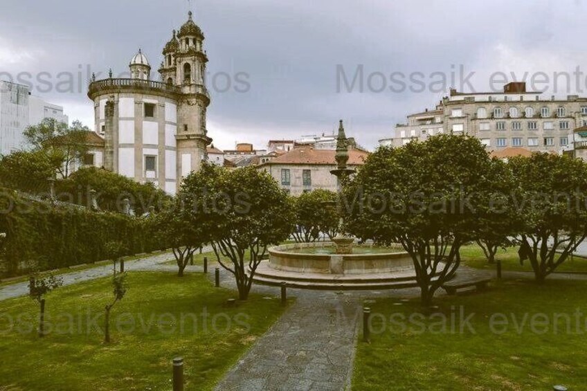 A historic building with a bell tower, surrounded by a well-maintained garden with a central fountain. 3