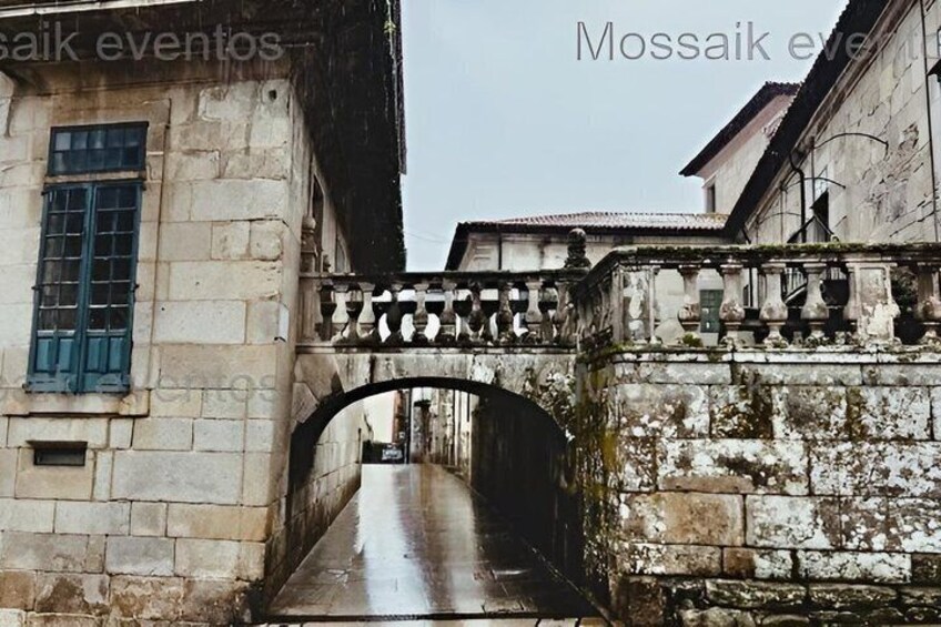 A stone bridge with a metal railing, leading to a building with a window and a door. 4