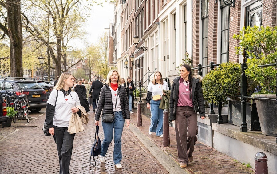 Pedestrians on a brick-paved street with parked cars and trees. 2