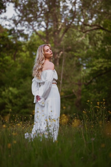 A person standing in a field with tall grass and trees in the background. 5