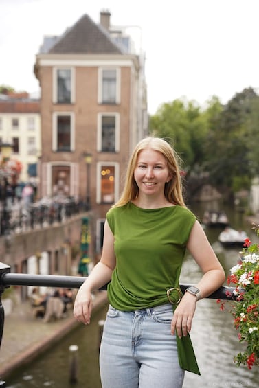 A person standing on a bridge with a river and buildings in the background. 5