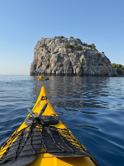 A yellow kayak on calm water with a rocky island in the background. 2