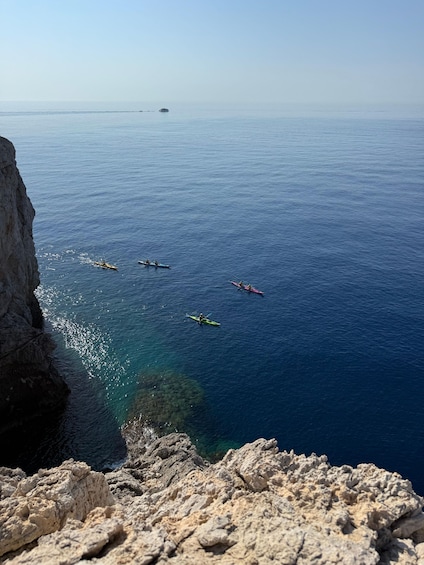 Kayakers on a calm sea with a rocky coastline. 2