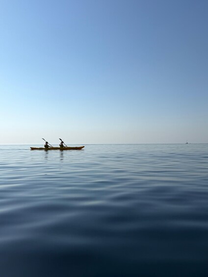 A calm sea with two people rowing a canoe. 4