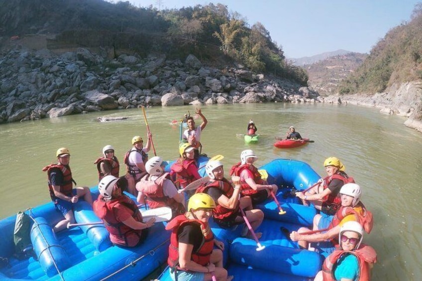 A group of people rafting on a river surrounded by rocky terrain and hills. 2