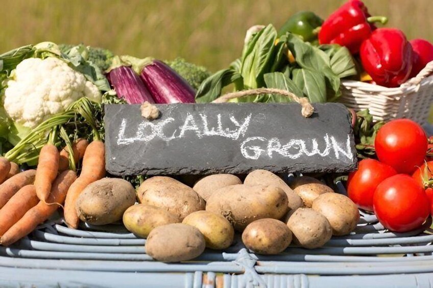 A variety of vegetables including carrots, potatoes, tomatoes, and leafy greens, with a sign indicating they are locally grown. 3