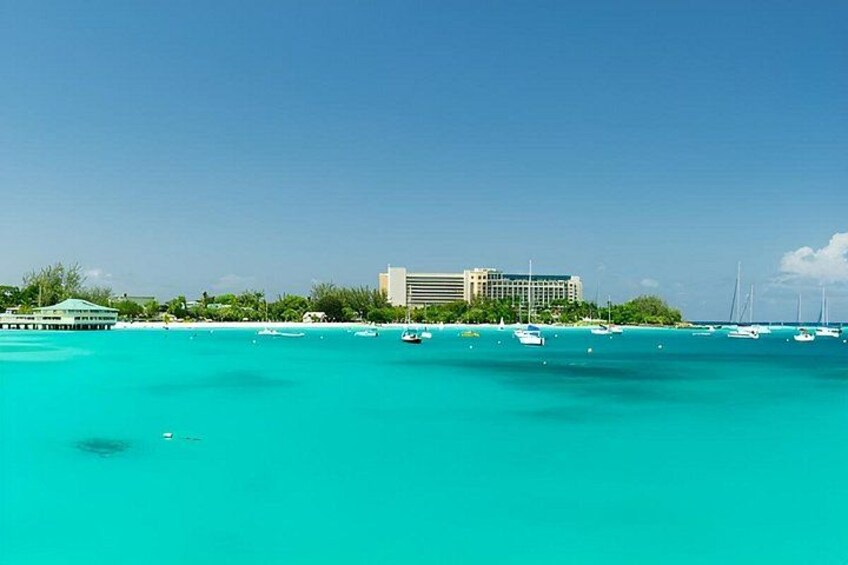 A coastal scene with turquoise waters, a hotel, and sailboats. 5