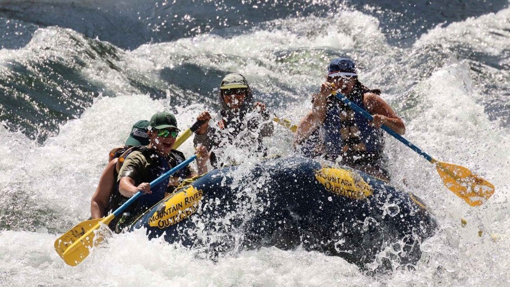 A group of people rafting on a river with white water rapids. 2