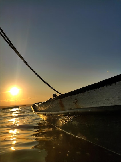 A boat's hull reflecting the sun on calm water during sunset. 4