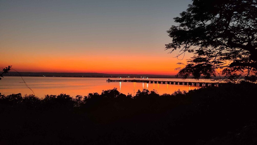 A sunset over a calm body of water with a pier extending into the water. 2