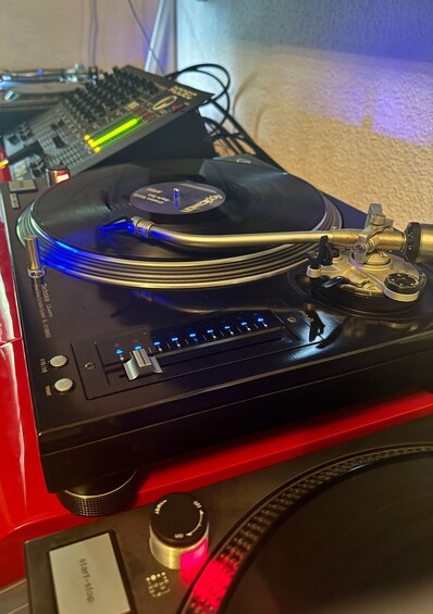 A turntable with a record, cables, and a mixer. 5