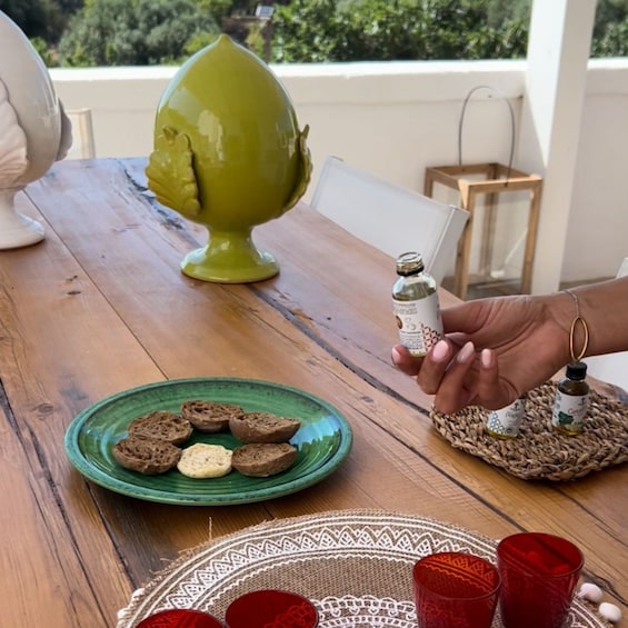 A wooden table with a green plate of cookies, a decorative vase, and a hand holding a small bottle. 5