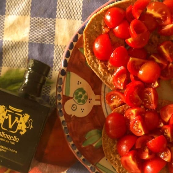 A plate with toasted bread topped with cherry tomatoes and a bottle of olive oil. 3