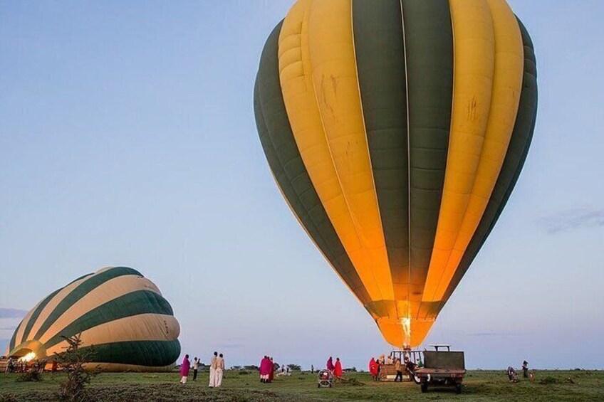 Two hot air balloons on the ground with people around them. 2