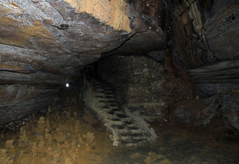 A cave with a spiral staircase descending into darkness. 2