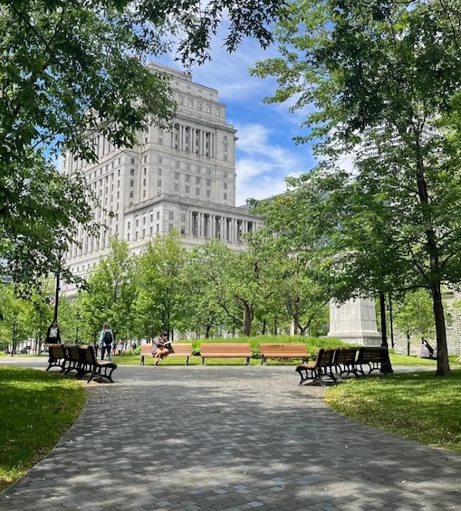 A park with benches and a large building in the background. 2
