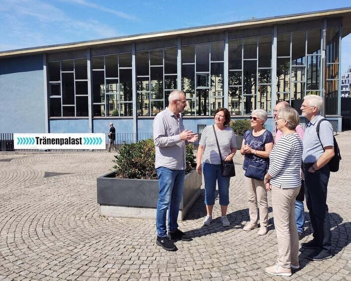 A group of people standing in front of a building with a sign that reads 'Tränchenpalast.' 3