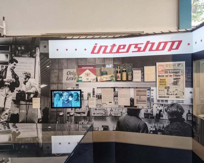 A store named 'intershop' with a TV screen, various posters, and shelves with products. 5