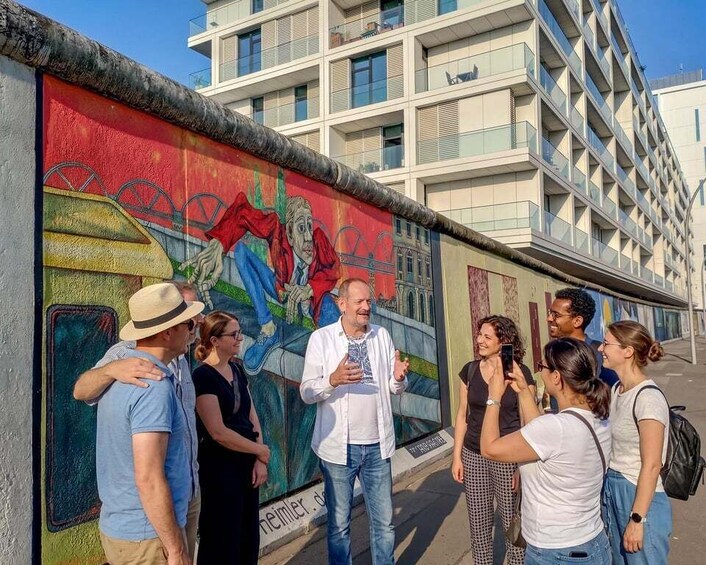 A group of people standing by a colorful mural on a building. 4