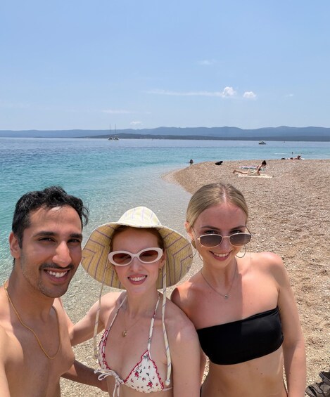 Three people at a beach with clear water and distant mountains. 5
