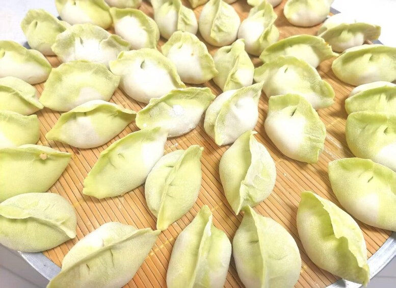 A tray of green dumplings on a bamboo mat. 3