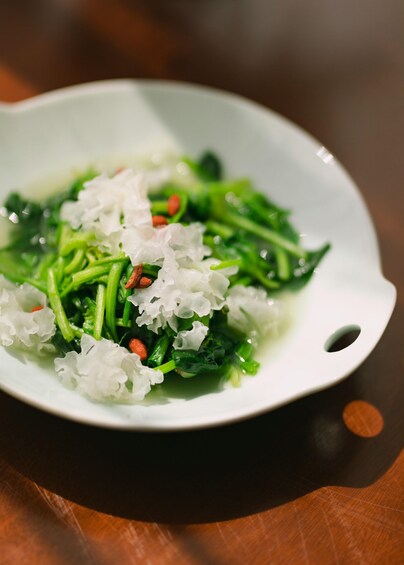 A white bowl containing a dish of green vegetables and white rice. 2