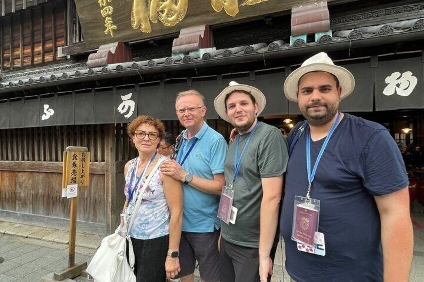 A group of people standing in front of a traditional Japanese building with a signboard. 3