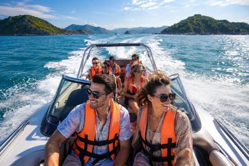 A group of people on a boat with life jackets, surrounded by water and distant green islands. 5
