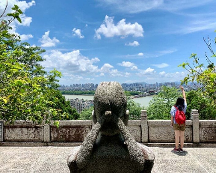 A statue of a figure with a raised arm, overlooking a river and cityscape. 2