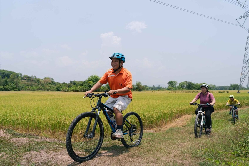 Two cyclists on a dirt path through a field with power lines in the background. 2