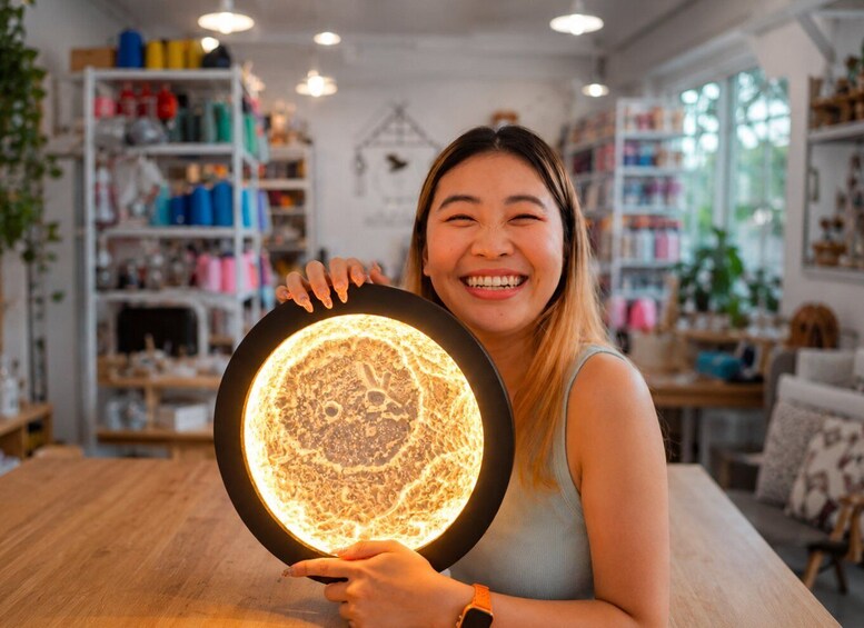 A person holding a glowing circular object in a well-lit indoor space with shelves of colorful items. 2