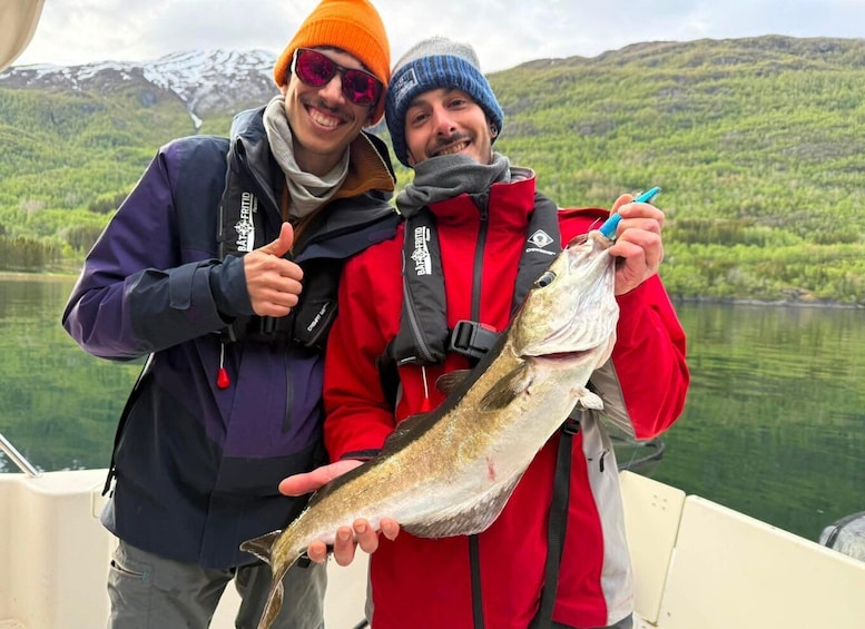 Two people on a boat holding a fish. 1